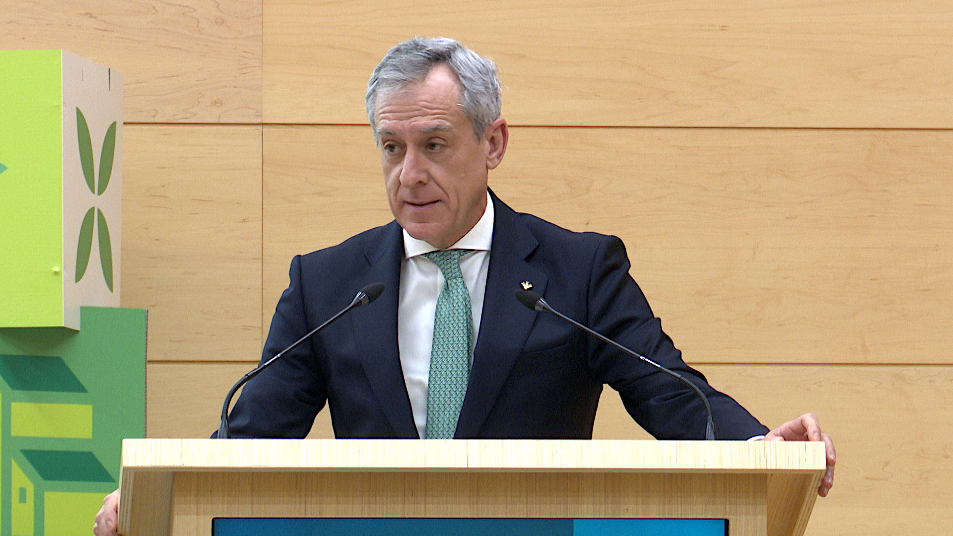 Intervención Javier López Martín, Presidente de Fundación Eurocaja Rural Intervención desde el atril durante el acto institucional Empuéblate La Rioja. Lleva traje oscuro y corbata verde mientras habla ante los micrófonos. Al fondo se ven paneles decorativos con ilustraciones relacionadas con el entorno rural en tonos verdes.