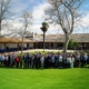 Grupo numeroso de personas posando al aire libre sobre un jardín, durante un encuentro entre empresas y talento joven del programa Campus Talento, en un espacio con edificios rurales y árboles al fondo.